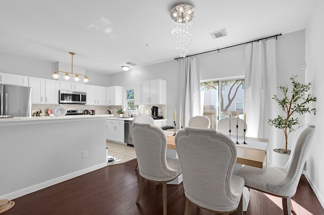 dining room featuring visible vents, plenty of natural light, an inviting chandelier, and wood finished floors