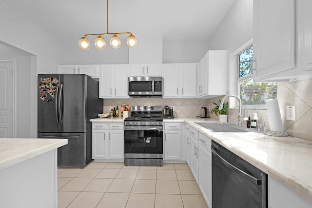 kitchen featuring light tile patterned floors, appliances with stainless steel finishes, a sink, white cabinetry, and backsplash