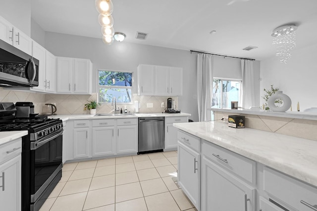 kitchen featuring light tile patterned floors, stainless steel appliances, a sink, visible vents, and decorative backsplash