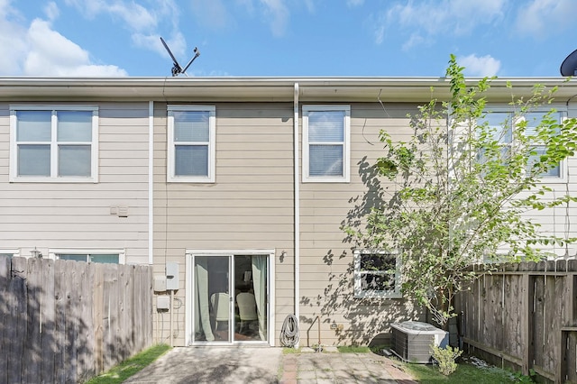 back of property with central AC unit, fence, and a patio