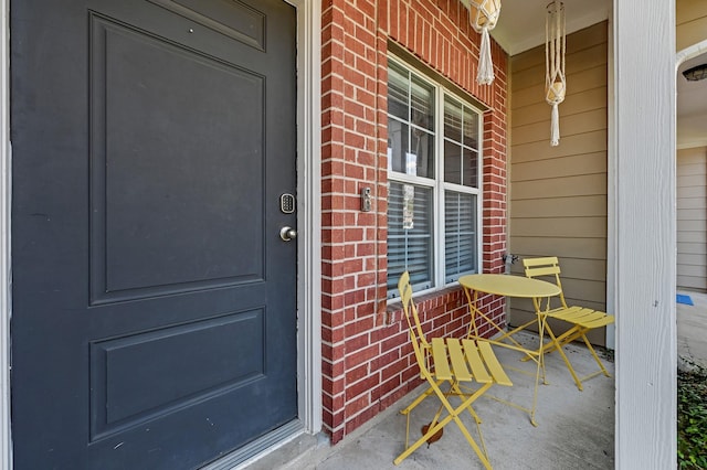 property entrance with a porch and brick siding