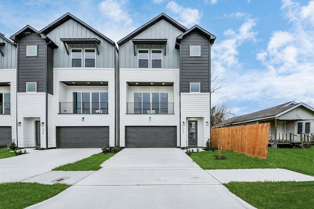 view of front facade with board and batten siding, a front lawn, driveway, and an attached garage