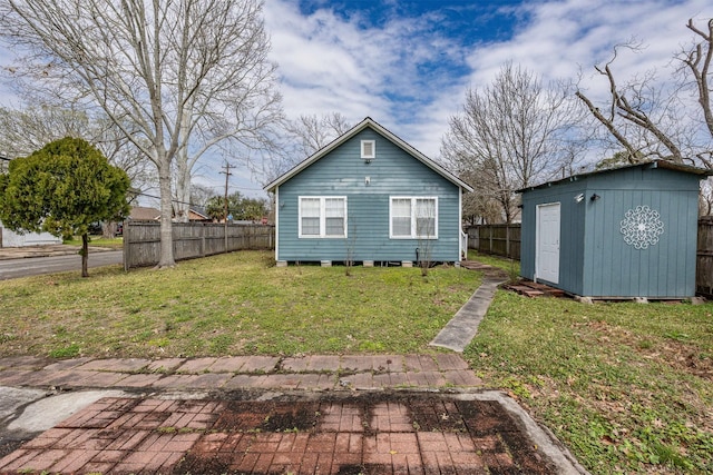 rear view of house featuring an outbuilding, a yard, a shed, and fence