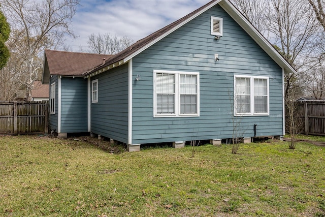 back of property featuring a shingled roof, a lawn, and fence