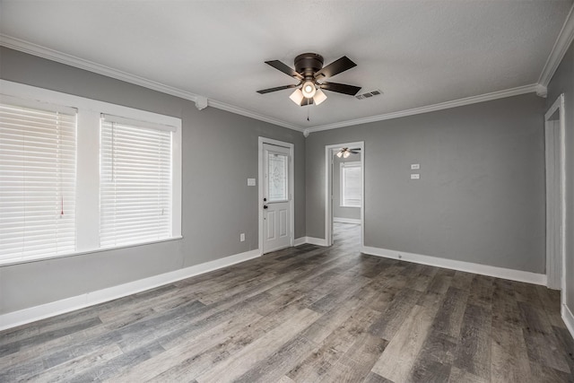 empty room with ceiling fan, wood finished floors, visible vents, baseboards, and crown molding