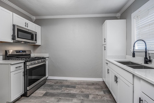 kitchen featuring crown molding, appliances with stainless steel finishes, a sink, and wood finished floors