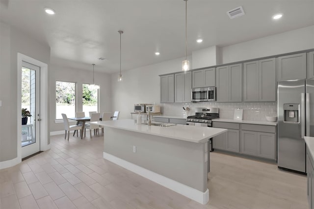 kitchen with visible vents, appliances with stainless steel finishes, a sink, and gray cabinetry