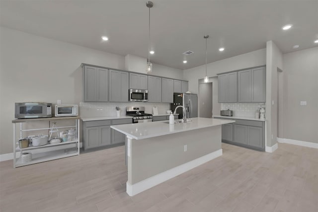 kitchen featuring appliances with stainless steel finishes, gray cabinets, visible vents, and a sink