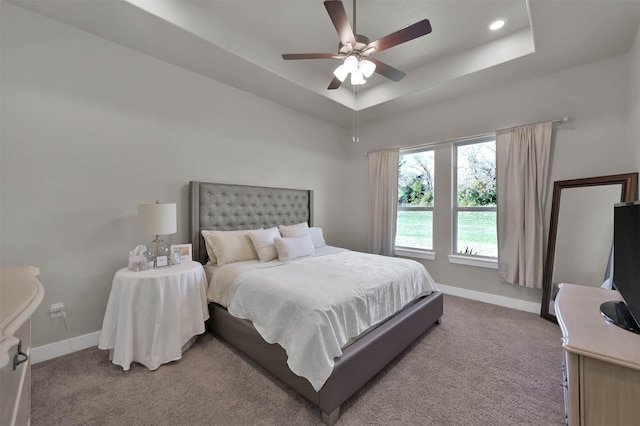 bedroom with a ceiling fan, a raised ceiling, carpet flooring, and baseboards