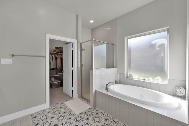 bathroom with a stall shower, a spacious closet, a bath, and tile patterned floors