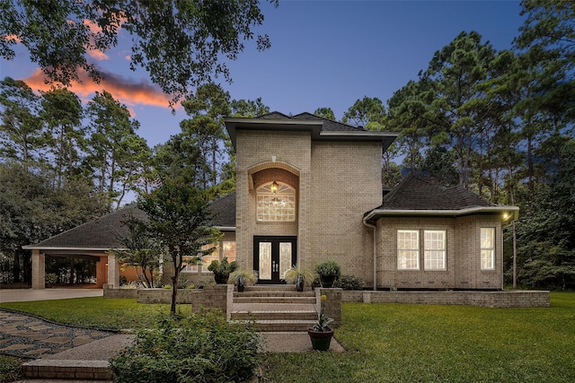 view of front facade featuring brick siding, a front lawn, and french doors