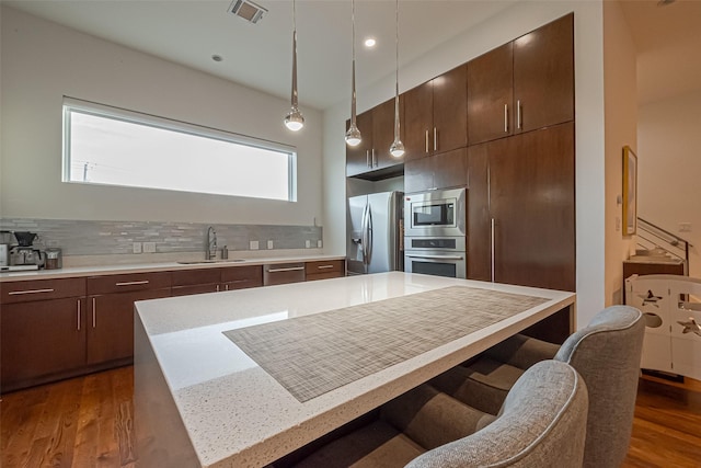 kitchen with dark wood-style floors, a breakfast bar area, stainless steel appliances, visible vents, and a sink