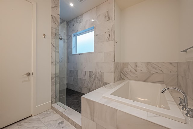 bathroom with marble finish floor, a garden tub, and tiled shower