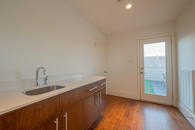 kitchen featuring a sink, visible vents, baseboards, light countertops, and light wood finished floors