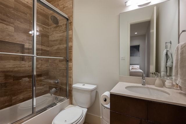 bathroom with enclosed tub / shower combo, vanity, and toilet