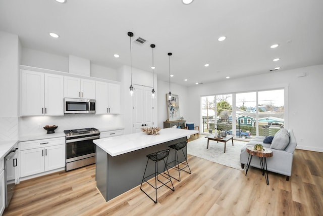 kitchen with light wood finished floors, visible vents, appliances with stainless steel finishes, and tasteful backsplash