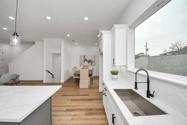 kitchen featuring recessed lighting, light countertops, light wood-style floors, white cabinetry, and a sink