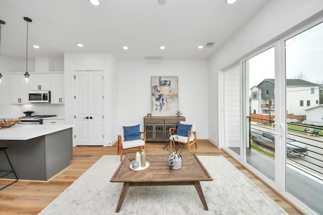 living area with baseboards, light wood-style floors, visible vents, and recessed lighting