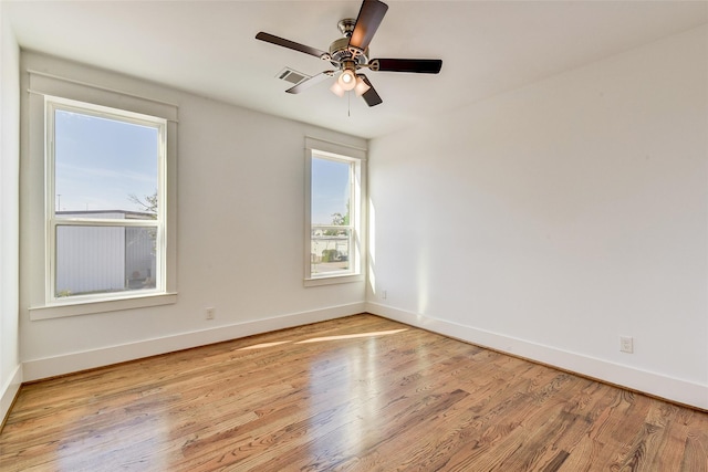 empty room with ceiling fan, light wood finished floors, visible vents, and baseboards