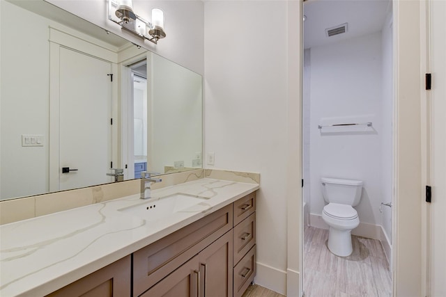 bathroom featuring toilet, vanity, visible vents, and baseboards