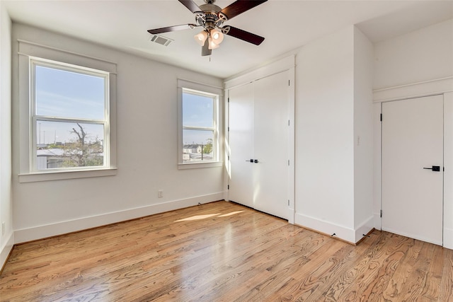 unfurnished bedroom with multiple windows, light wood-type flooring, visible vents, and baseboards