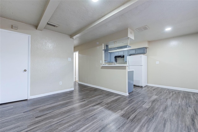 interior space with visible vents, wood finished floors, freestanding refrigerator, and baseboards