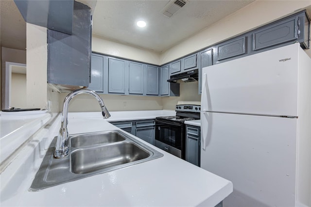 kitchen featuring freestanding refrigerator, light countertops, under cabinet range hood, a sink, and range with electric stovetop