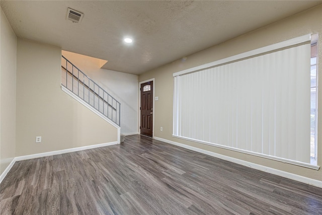 interior space with baseboards, visible vents, dark wood-type flooring, stairs, and a textured ceiling