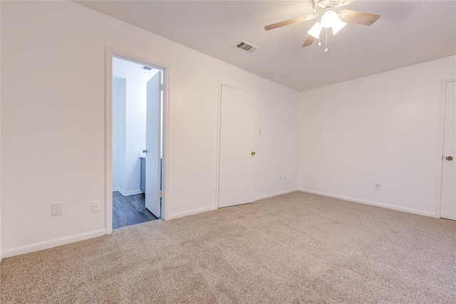 carpeted spare room featuring visible vents, ceiling fan, a textured ceiling, and baseboards