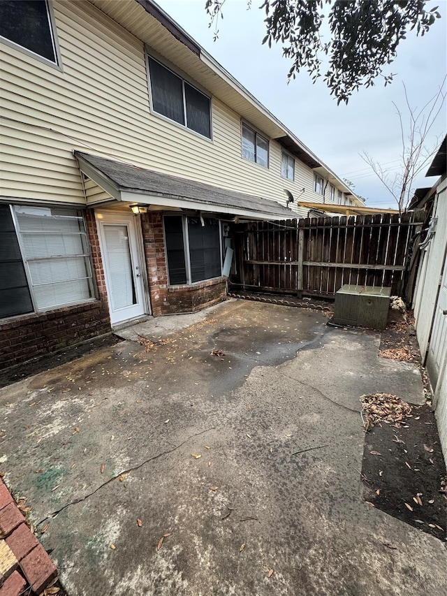 rear view of house with a patio, brick siding, and fence