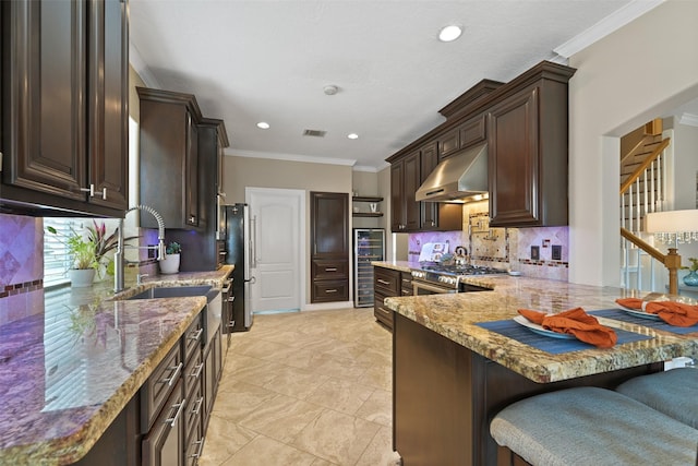 2433 La Rochelle Ct, Seabrook, TX 77586 - kitchen with wine cooler, range hood, light stone countertops, and dark brown cabinets