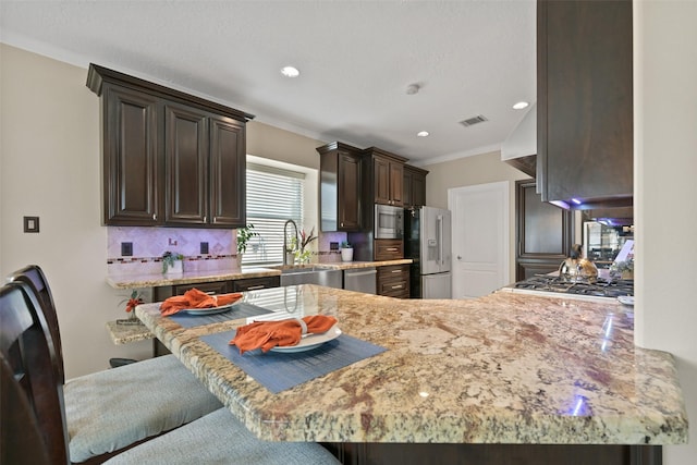 2433 La Rochelle Ct, Seabrook, TX 77586 - kitchen with dark brown cabinets, a sink, stainless steel appliances, visible vents, and ornamental molding