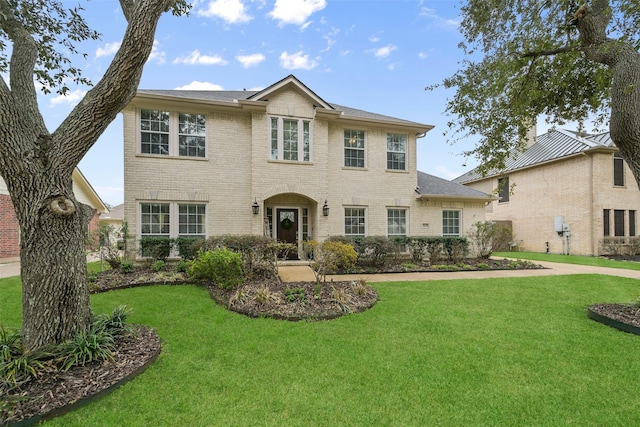 colonial home with brick siding and a front yard