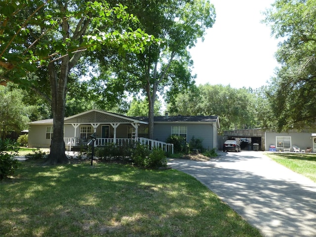 ranch-style house featuring covered porch, an attached carport, a front lawn, and concrete driveway