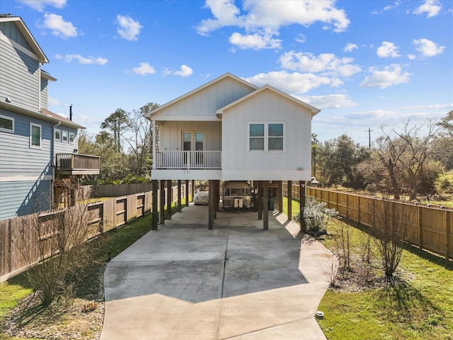 beach home featuring board and batten siding, fence, a carport, and concrete driveway