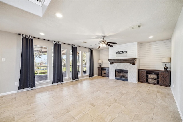 unfurnished living room with a textured ceiling, a fireplace, visible vents, and a ceiling fan