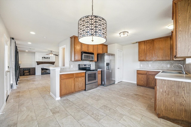 kitchen featuring appliances with stainless steel finishes, a fireplace, a sink, and brown cabinets