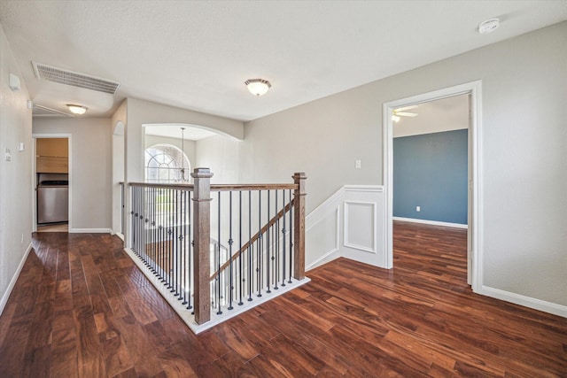 hall featuring a wainscoted wall, visible vents, an upstairs landing, and wood finished floors