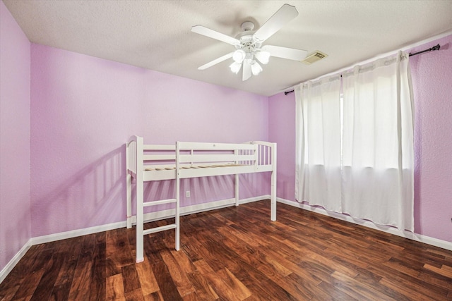 unfurnished bedroom featuring visible vents, ceiling fan, baseboards, and wood finished floors