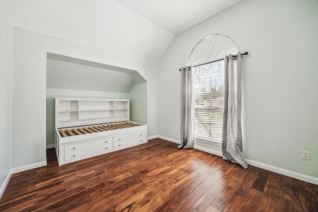 interior space featuring lofted ceiling, wood finished floors, and baseboards