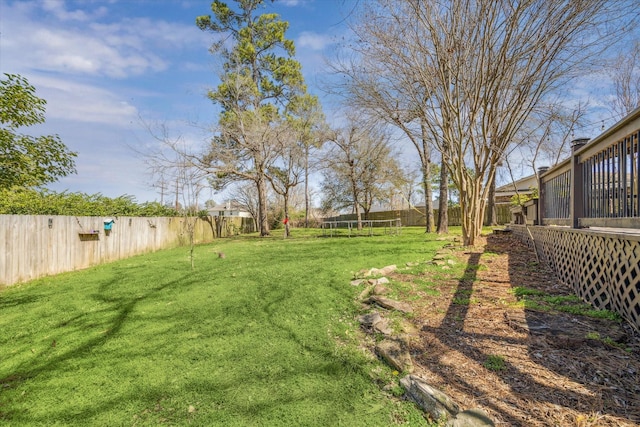 view of yard featuring a trampoline and a fenced backyard