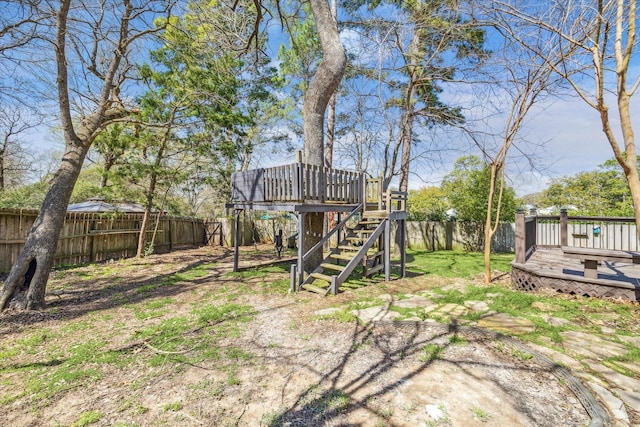 view of yard featuring a deck, a fenced backyard, and stairs