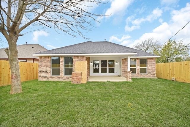 rear view of house with brick siding, a lawn, and a fenced backyard