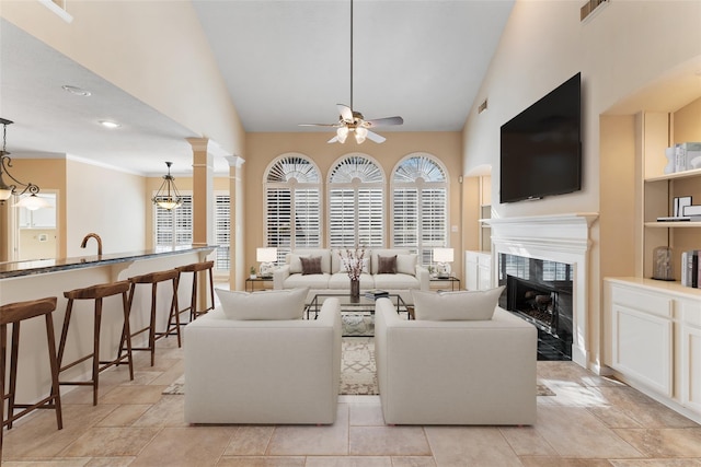 living area featuring a fireplace, visible vents, a ceiling fan, plenty of natural light, and ornate columns