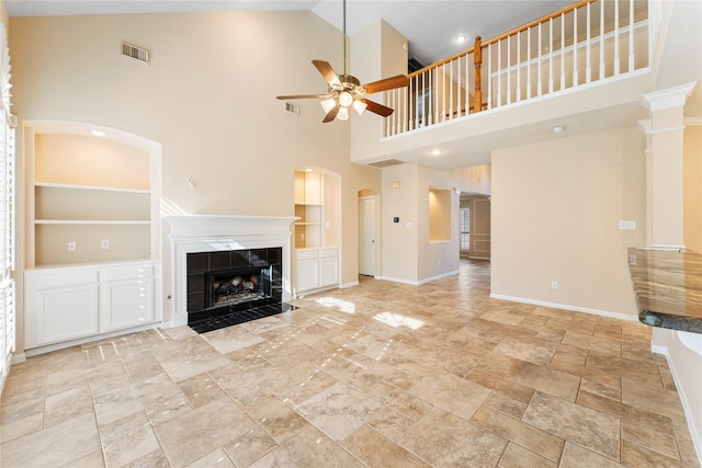 unfurnished living room featuring baseboards, visible vents, a tiled fireplace, ceiling fan, and built in shelves