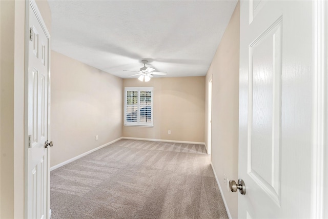 empty room featuring light colored carpet, ceiling fan, and baseboards