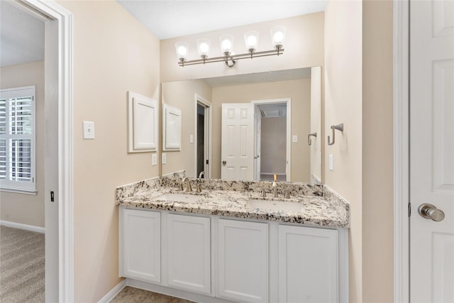 full bathroom with double vanity, baseboards, and a sink