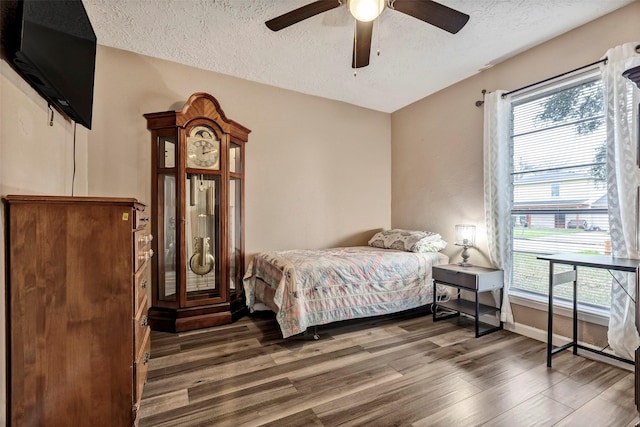 bedroom featuring a ceiling fan, a textured ceiling, baseboards, and wood finished floors