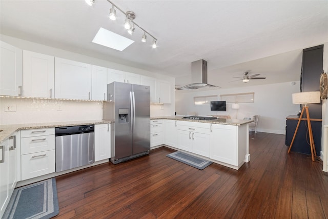 kitchen with a peninsula, stainless steel appliances, wall chimney exhaust hood, and dark wood-type flooring