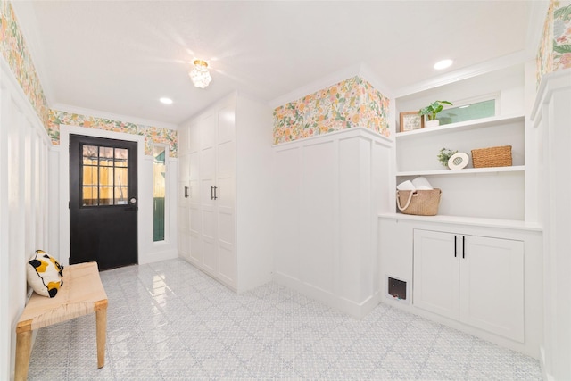 foyer entrance with recessed lighting, a decorative wall, wainscoting, and crown molding